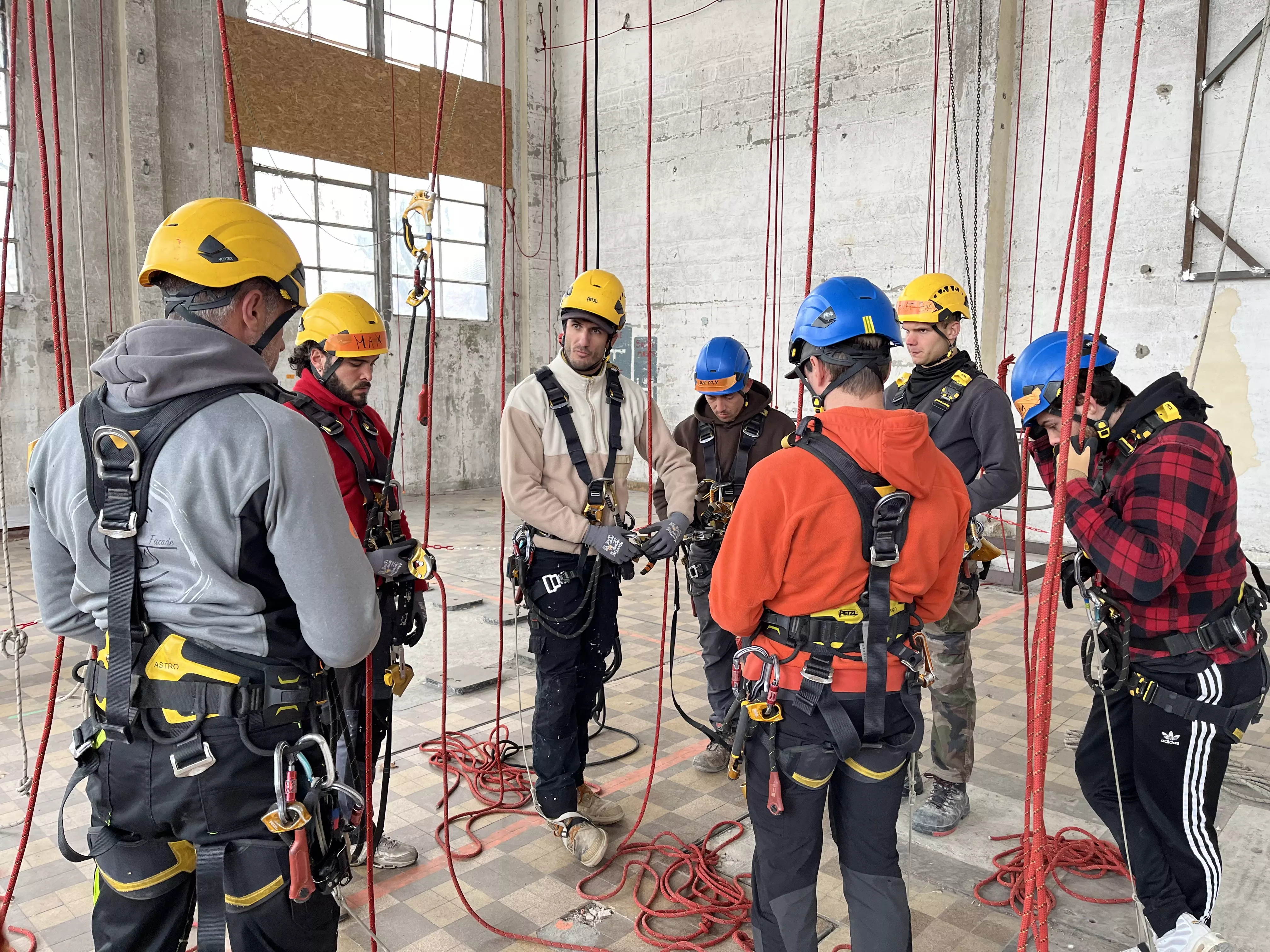 Stagiaires en formation cordiste, équipés de harnais et casques, apprenant les techniques de travail en hauteur avec cordes
